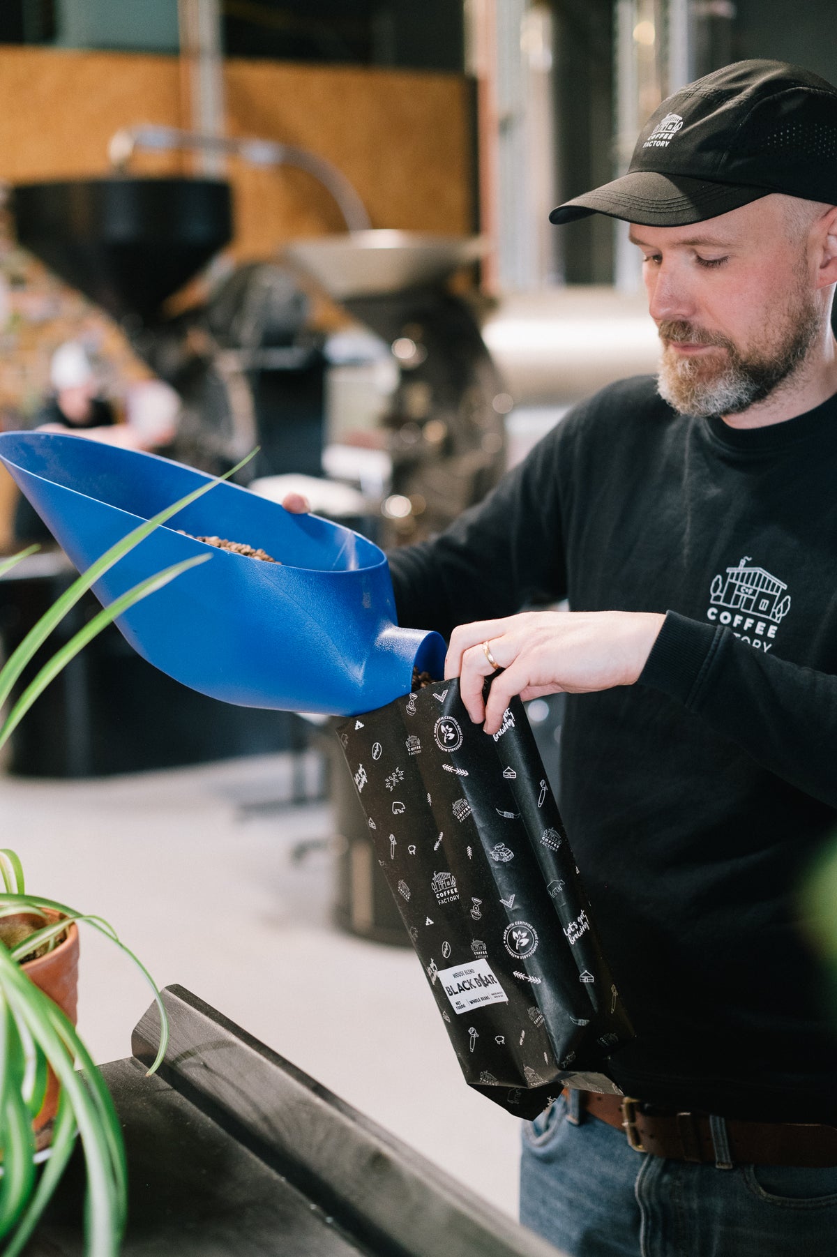 Danny filling a Coffee Factory bag with freshly roasted beans in the roastery